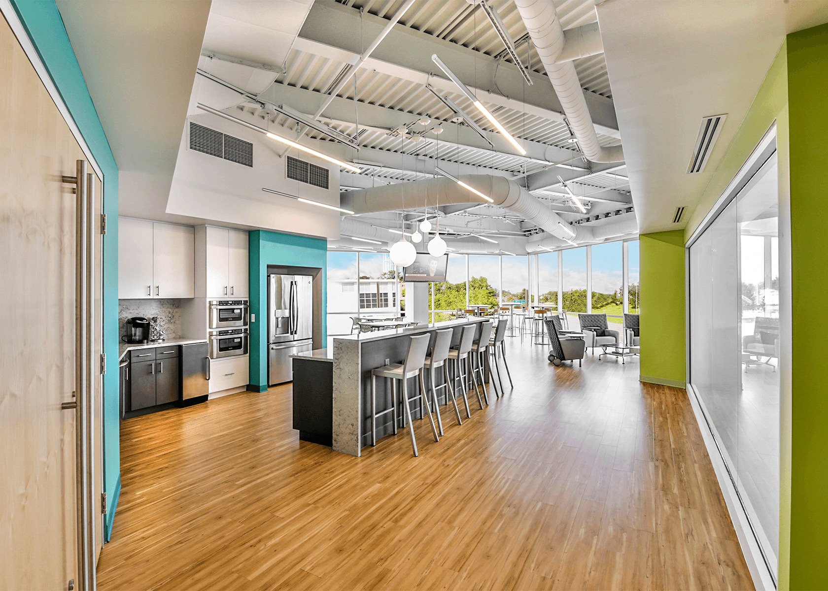 large café/break area with bright green and turquoise walls and light wood floors
